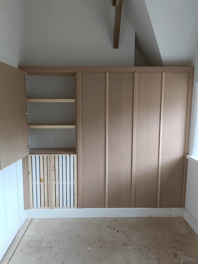 Interior view of a room showcasing built-in cabinetry made from MDF, featuring open shelves and a wooden slatted section at the bottom.