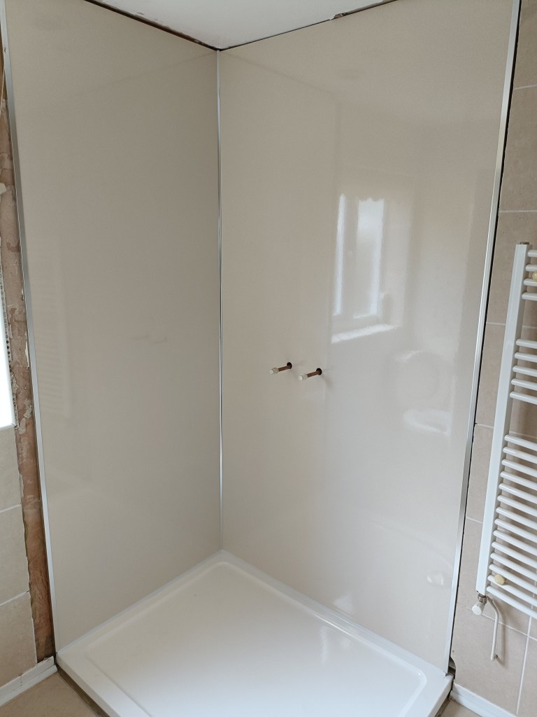 A clean and modern shower stall with shiny, white walls and a white shower base, featuring no visible fixtures or accessories.